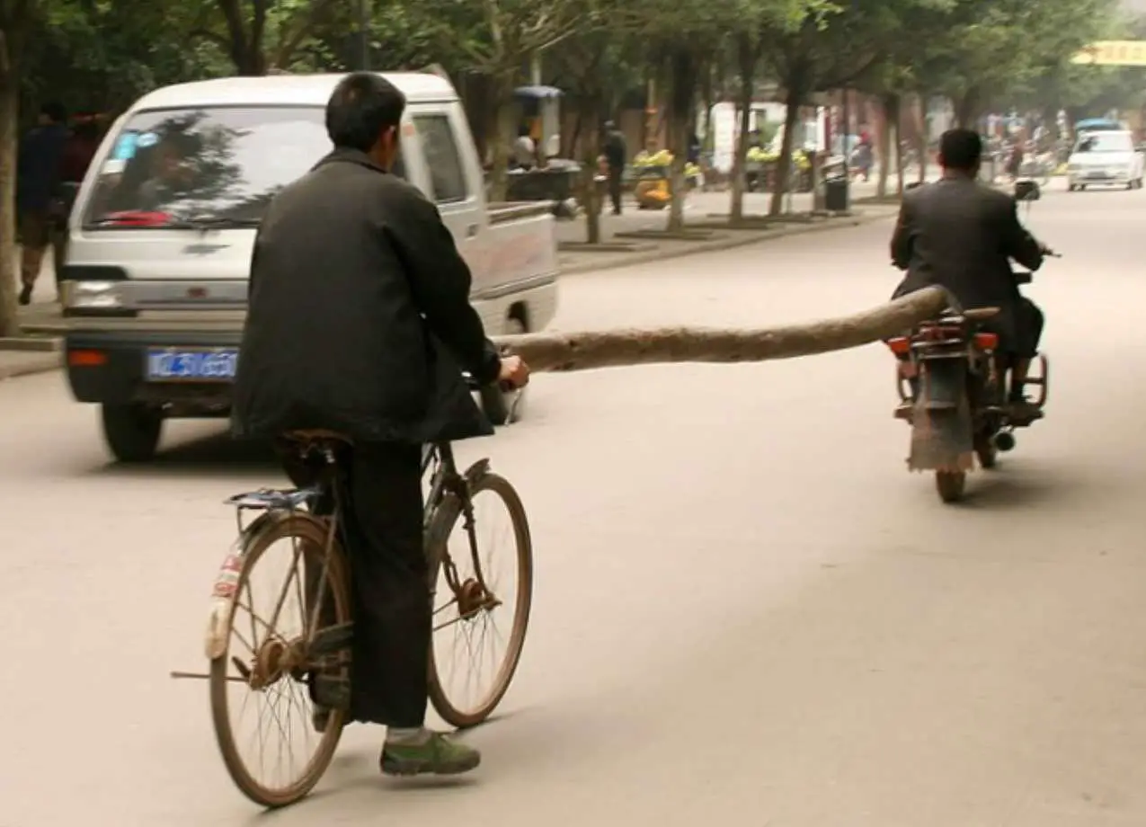 Transporting Large Log By Scooter And Bicycle